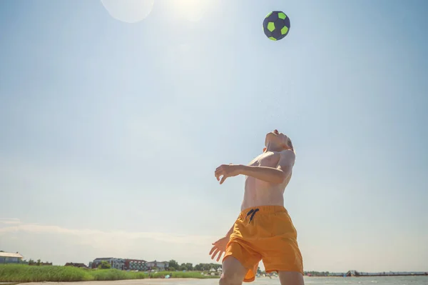 夏の晴れた日に太陽の光を背景にビーチでボールとバレーボールをプレイ10代の男の子の肖像画 — ストック写真