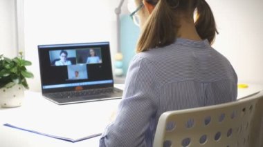 Sınıf arkadaşları ve öğretmeniyle çevrimiçi derste salgın sırasında dizüstü bilgisayar kullanan sevimli liseli kız.