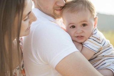 Mutlu genç baba kucağında güzel gözlü tatlı bir çocuk ve güneşli ışıkta birlikte anın tadını çıkarıyor.