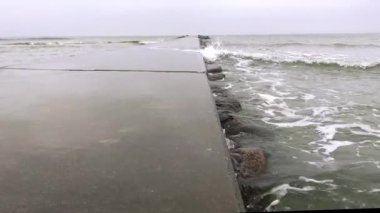 Kuzey Almanya 'da Baltık Denizi' nde rüzgarlı bulutlu havada ahşap dalgakıranın 4k videosu