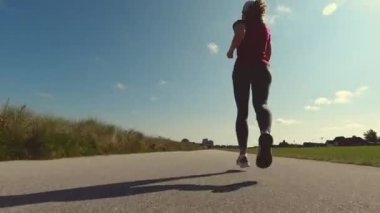 60fps 4K spor elbiseli bir kadının yaz sabahı koşu videosu.