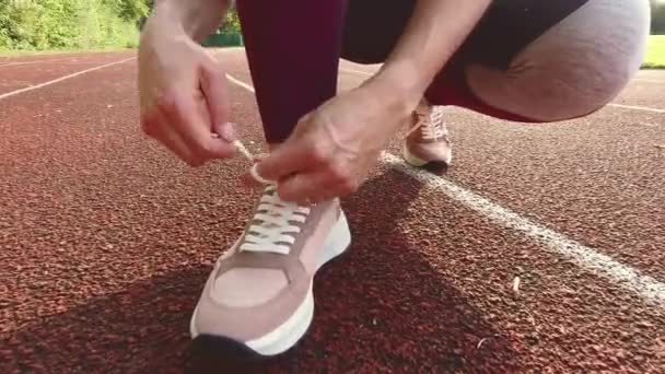 60英尺4K的视频 内容是女运动员在日落时分在体育场系鞋带和慢跑 — 图库视频影像