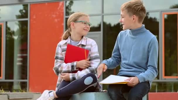 Porträtt Två Glada Skolbarn Som Sitter Skolgården Och Gärna Pratar — Stockvideo