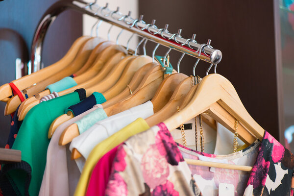 Variety of clothes hanging on rack in boutique