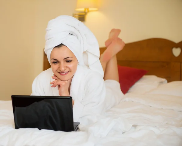 Mulher bonita em roupão de banho com laptop — Fotografia de Stock