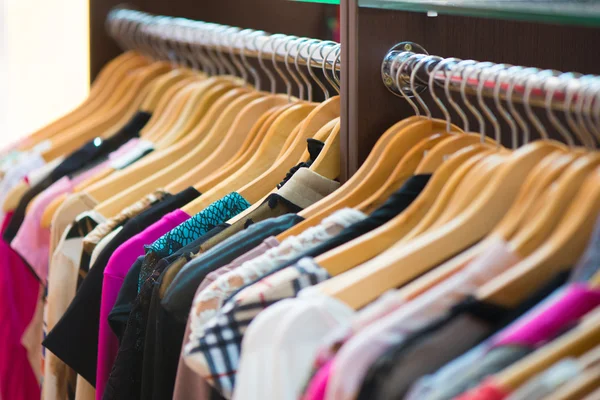 Variety of clothes hanging on rack in boutique Stock Photo