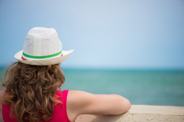 Kıvırcık saçlı kız okyanus sahilinde. Arkadan görünüş.