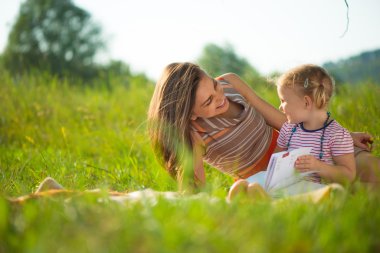 Genç ve güzel annesi okuma kitabı küçük kızına
