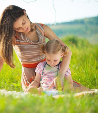 Genç ve güzel annesi okuma kitabı küçük kızına