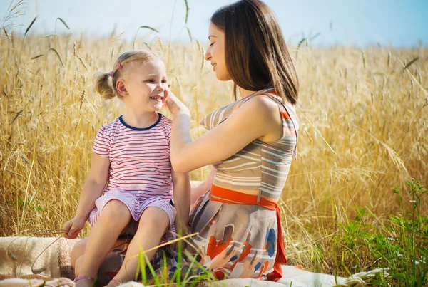 Jovem mãe com filha bonita no campo de trigo — Fotografia de Stock