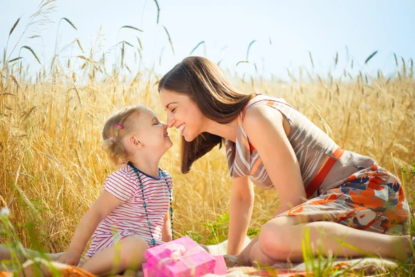 Jovem mãe feliz com filhinha em campo no dia de verão — Fotografia de Stock