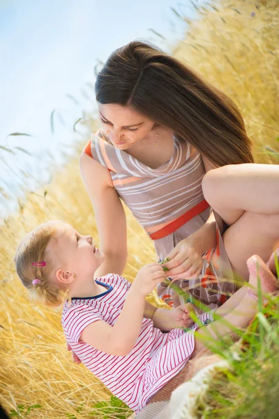 Joven madre con hija pequeña en el campo de trigo — Foto de Stock