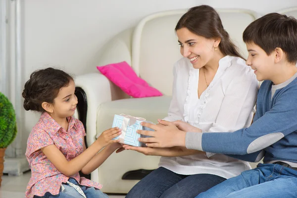 Mother and older brother presenting gift box to little sister on — Stock Photo, Image