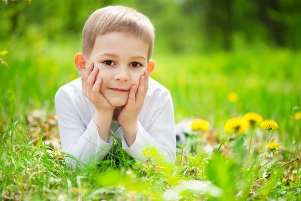 Petit garçon souriant couché dans l'herbe verte — Photo