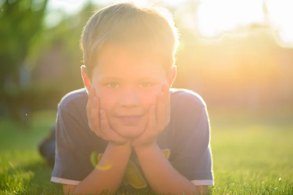 Petit garçon souriant couché dans l'herbe verte — Photo