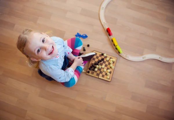 Söt liten flicka sitter på golvet och leker — Stockfoto