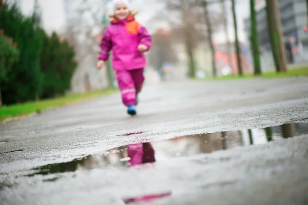 Маленька щаслива дівчинка стрибає в калюжу — стокове фото