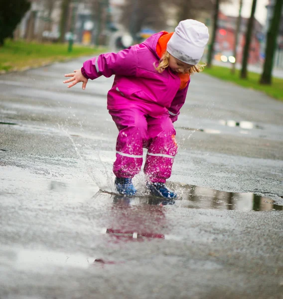 Liten glad tjej hoppning i pöl — Stockfoto