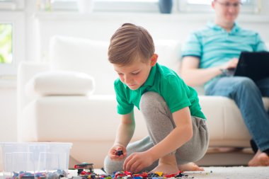 Little boy play, father works with laptop