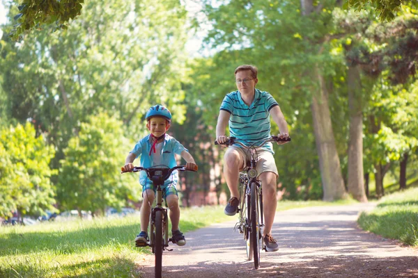 Happy father and son ride on bikes — Stock Photo, Image