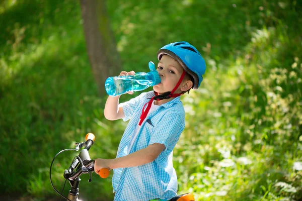 Lille pojken med cykeln dricker vatten — Stockfoto