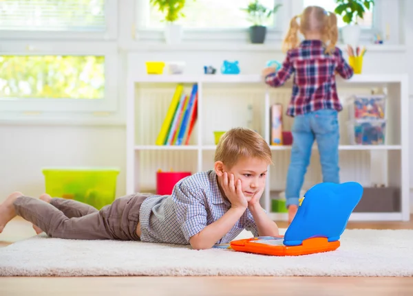 Piccolo ragazzo intelligente giocare con il computer portatile a casa — Foto Stock