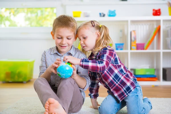 Dos niños inteligentes explorando el globo — Foto de Stock