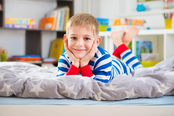 Χαριτωμένο μικρό αγόρι στο πιτζάμες βρίσκεται στο κρεβάτι — Φωτογραφία Αρχείου