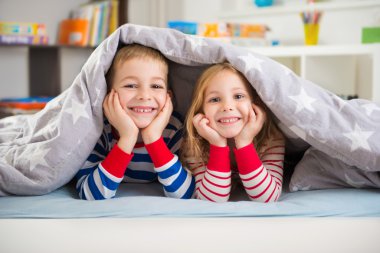 Battaniyenin altında yatan iki mutlu çocuk
