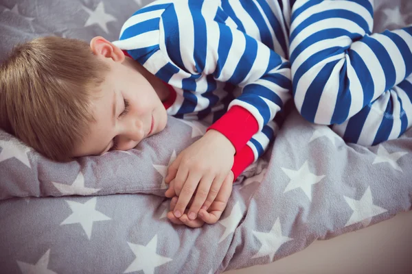 Aranyos kis fiú alszik az ágyban pajames. Fokus fenti — Stock Fotó