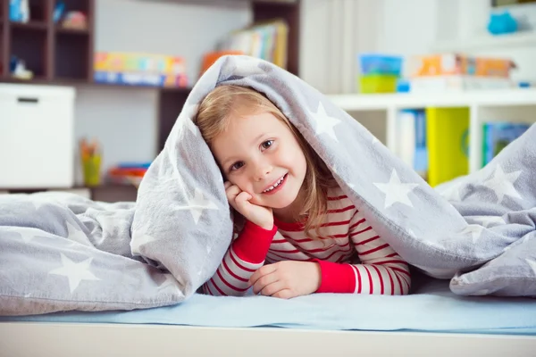 Hübsches kleines Mädchen unter Decke liegend — Stockfoto