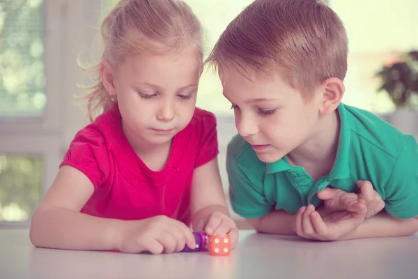 Twee gelukkige kinderen spelen met dobbelstenen — Stockfoto