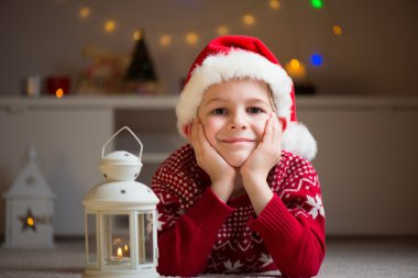 Kırmızı şapka ve Noel Baba bir dakika içinde yerde yatarken mutlu sevimli çocuk