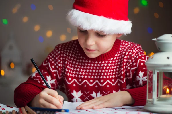 Niño de Navidad escribiendo carta a Santa Claus carta en sombrero rojo —  Fotos de Stock