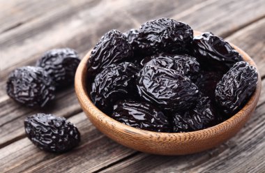 Prunes on a wooden background clipart