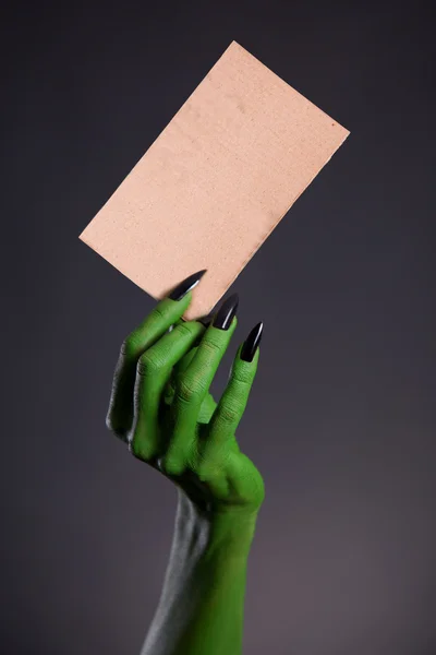 Green skin hand with sharp nails holding empty piece of cardboar — Stock Photo, Image