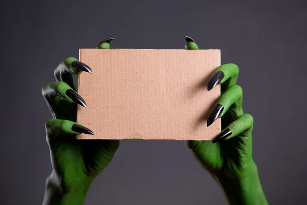 Green monster hands holding empty piece of cardboard — Stock Photo, Image