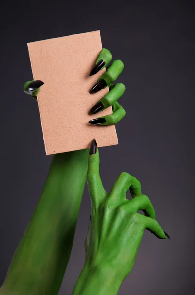 Green monster hands with black nails holding blank piece of cardboard