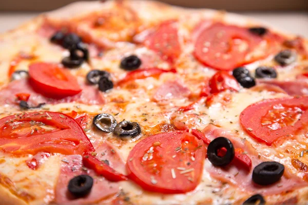 Close-up shot van Italiaanse pizza met ham, tomaten en olijven — Stockfoto