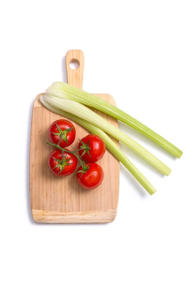 Tomatoes and celery sticks on chopping board — Stock Photo, Image