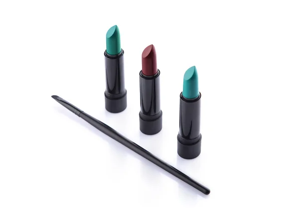 Makeup brush and three lipsticks — Stock Photo, Image