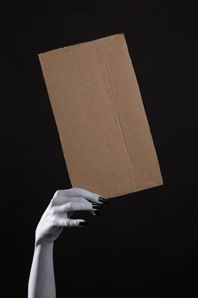 Hand with black nails holding cardboad — Stock Photo, Image