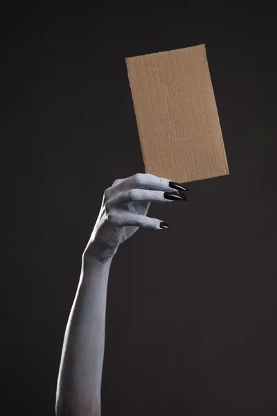 Hand with black nails holding cardboad — Stock Photo, Image