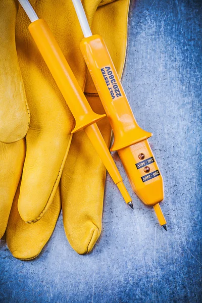 Yellow electrical tester and protective gloves — Stock Photo, Image