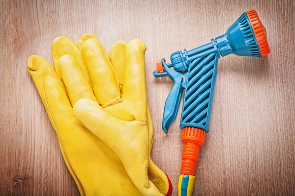 Safety gloves and garden hose nozzle — Stock Photo, Image