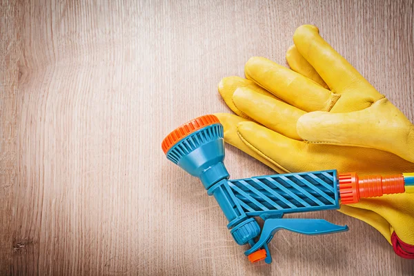 Safety gloves and garden hose nozzle — Stock Photo, Image