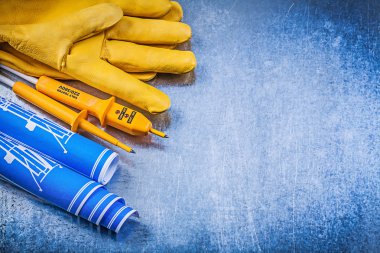 Elektrik test cihazı, eldiven ve mavi haddelenmiş inşaat planları