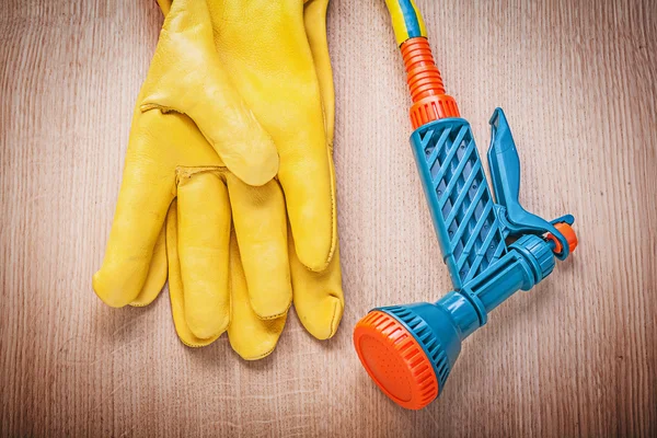 Safety gloves and garden hose nozzle — Stock Photo, Image