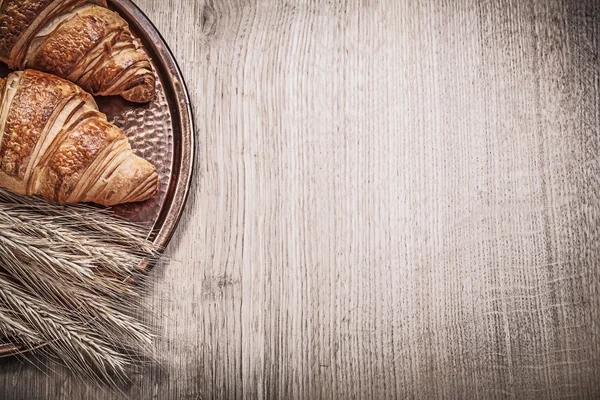 Золоті пшеничні житні вуха свіжоспечені круасани мідний лоток на дереві — стокове фото