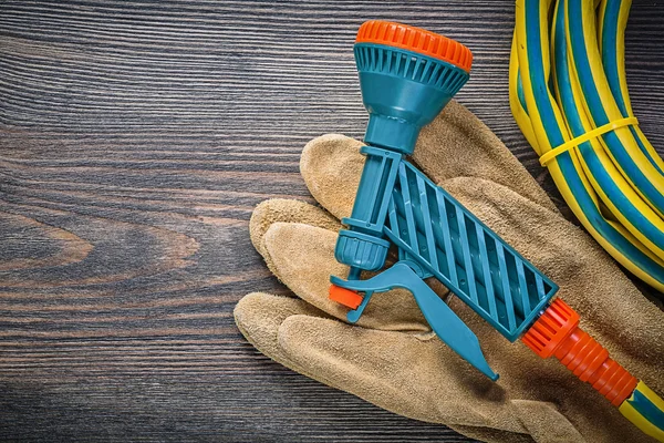Garden rubber hose water sprinkler safety gloves on wooden board — Stock Photo, Image